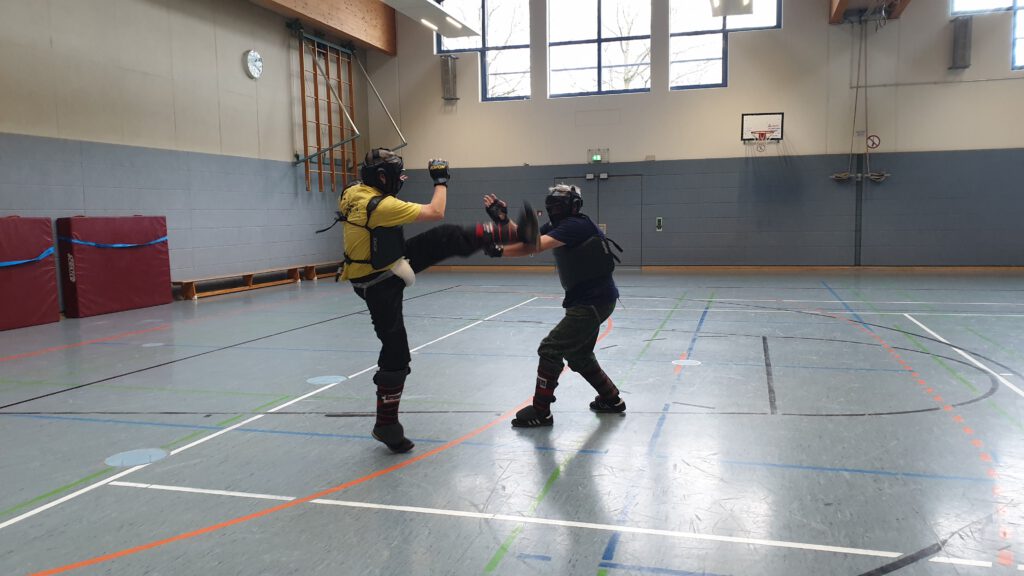 Oliver Solbach mit hohem halbkreisförmiger Tritt zum Kopf, gerade in der Ausführung, beim Privatunterricht. Winter 2024 in Trainingshalle.