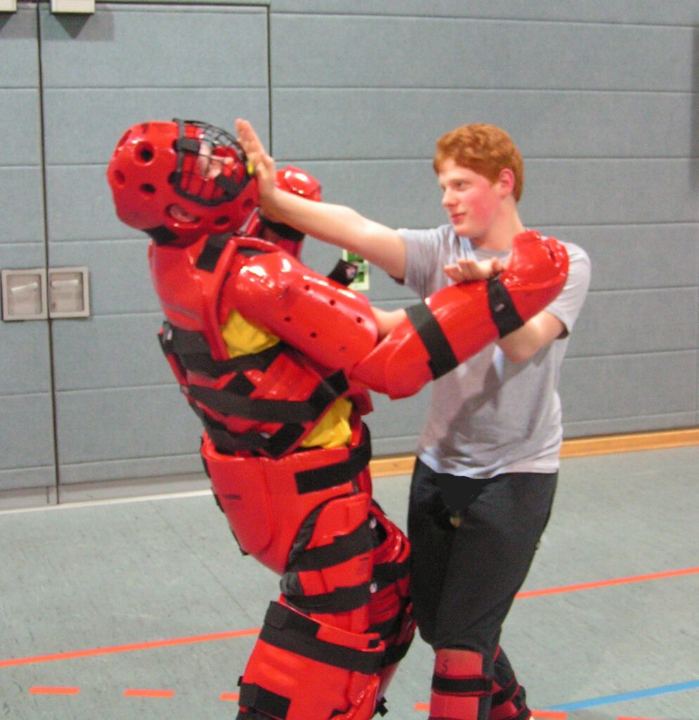 Sohn von Oliver Solbach und er beim Nahkampf-Training mit Vollschutz-Anzug Red Man. Abwehr Handangriff.